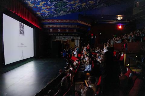 WHY ARE YOU YOU? Screening Image of a movie theater full of people watching a screening of WHY ARE YOU YOU?